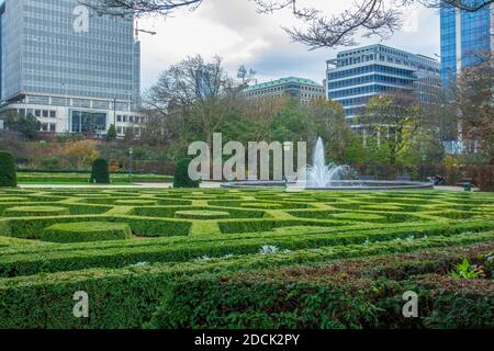 Jardin botanique impressionnant dans le centre-ville de Bruxelles à la fin de l'automne avec buissons topiaires et fontaine et ville en arrière-plan Banque D'Images