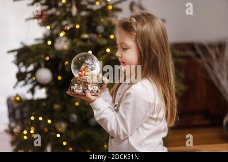 Fille regardant une boule de verre avec une scène de La naissance de Jésus-Christ dans une boule de verre Banque D'Images