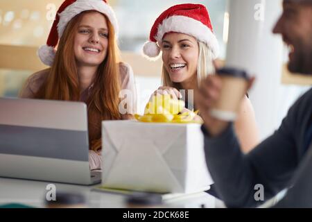Groupe de collègues célébrant Noël au bureau avec des cadeaux porter des chapeaux de père noël Banque D'Images