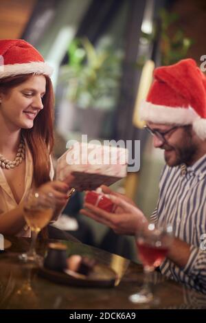 Un jeune couple amoureux est ravi des cadeaux du nouvel an à l'occasion d'une fête dans une atmosphère de vacances dans un restaurant. Ensemble, nouvel an, célébration Banque D'Images