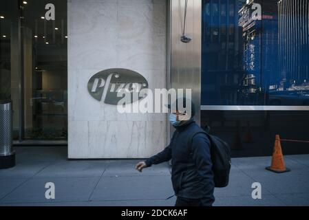 Manhattan, New York. 20 novembre 2020. Un homme portant un masque marche par le logo de Pfizer à l'extérieur du siège de la société sur la 42e rue Banque D'Images