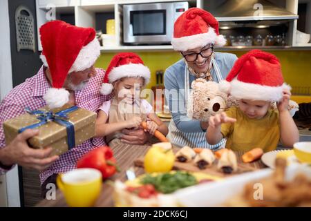 Grand-parent dans la cuisine dans une ambiance festive avec des cadeaux de Noël pour petits-enfants. Noël, famille, ensemble Banque D'Images