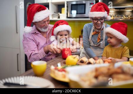 Grand-parent appréciant avec petits-enfants dans la préparation de repas de Noël dans une atmosphère festive. Noël, famille, ensemble Banque D'Images