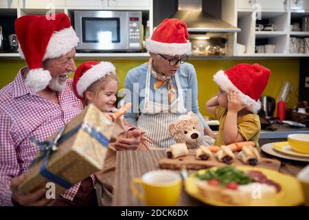 Les grands-parents aiment être avec des petits-enfants dans une ambiance festive dans la cuisine pour un Noël. Noël, famille, ensemble Banque D'Images