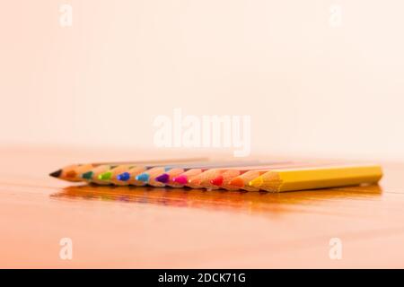 Gros plan sur une diagonale de douze crayons de couleur aligné sur un arrière-plan marron et blanc Banque D'Images