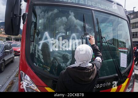 Bogota, Colombie. 21 novembre 2020. Des hommes à capuchon graffiti sur le verre d'un bus de service public dans la marche de Bogota contre le gouvernement du président Ivan Duque, rejetant également les meurtres de leaders sociaux. Crédit : Daniel Garzon Herazo/ZUMA Wire/Alay Live News Banque D'Images