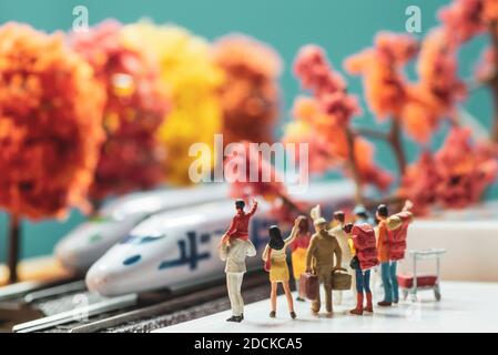 Figurines de jeu miniatures d'un groupe de passants en attente ou en agitant à un train à grande vitesse à une plate-forme en automne ou le concept de la saison d'automne - filtre de tons chauds Banque D'Images