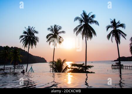 Coucher de soleil se reflétant sur la surface de l'eau au premier plan avec des cococotiers zone ao bang Bao à l'île de Koh Kood est un district de la province de Trat. Thaïlande. Banque D'Images