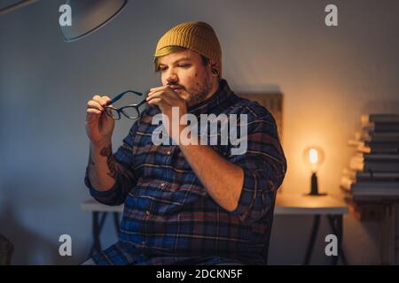 Un portrait de gros plan d'un jeune homme de taille basse le nettoyant lunettes optiques avant le port Banque D'Images