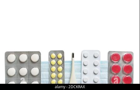 Pilules, vitamines et un thermomètre sur fond blanc pour le traitement de la grippe et du rhume Banque D'Images