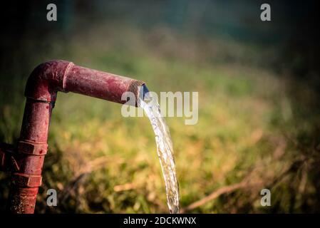 Gaspillage d'eau. De l'eau douce s'écoule d'un tuyau en acier. Banque D'Images