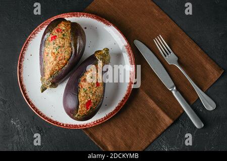 Aubergines semi-finées farcies de viande hachée avec épices sur le noir arrière-plan Banque D'Images