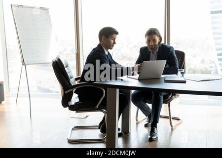 Des partenaires d'affaires souriants travaillent sur un ordinateur portable au bureau Banque D'Images