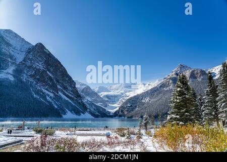 Fairmont Chateau Lake Louise en début d'hiver, jour ensoleillé le matin. Brume flottant sur la surface turquoise de l'eau. Ciel bleu clair, montagnes enneigées Banque D'Images