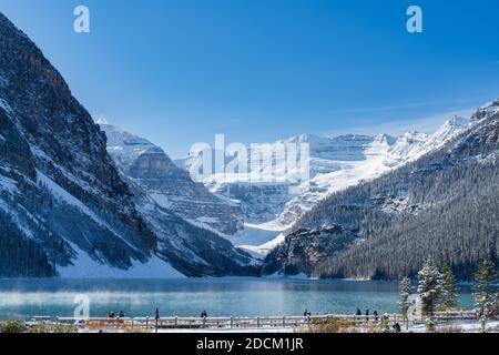 Lac Louise en début d'hiver, jour ensoleillé le matin. Brume flottant sur la surface turquoise de l'eau. Ciel bleu clair, montagnes enneigées en arrière-plan Banque D'Images