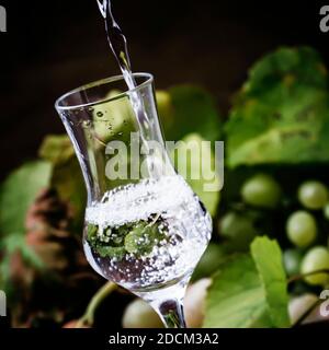 Boisson alcoolisée forte versée dans le verre à liqueur, la vie rustique, la concentration sélective et les DOF peu profondes Banque D'Images