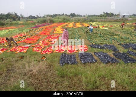 Les travailleurs bangladais collectent des tissus après les avoir séchés sous le soleil dans une usine de teinture à Narayanganj, au Bangladesh. Nazmul Islam/Alamy stock photo Banque D'Images