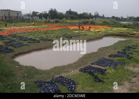 Les travailleurs bangladais collectent des tissus après les avoir séchés sous le soleil dans une usine de teinture à Narayanganj, au Bangladesh. Nazmul Islam/Alamy stock photo Banque D'Images