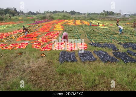 Les travailleurs bangladais collectent des tissus après les avoir séchés sous le soleil dans une usine de teinture à Narayanganj, au Bangladesh. Nazmul Islam/Alamy stock photo Banque D'Images