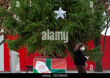 Southampton, Royaume-Uni, 21 novembre 2020. Une femme portant un masque et utilisant son téléphone mobile marche à côté d'un triste arbre de Noël décoré dans une étoile et quelques lumières qui ne sont pas allumées dans le centre de Southampton. Scènes générales du centre-ville de Southampton lors du second confinement national du Covid-19 en Angleterre. Banque D'Images