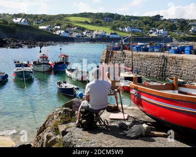 Un artiste au travail sur le port de Coverack, Cornwall. Banque D'Images