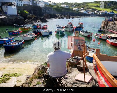 Un artiste au travail sur le port de Coverack, Cornwall. Banque D'Images