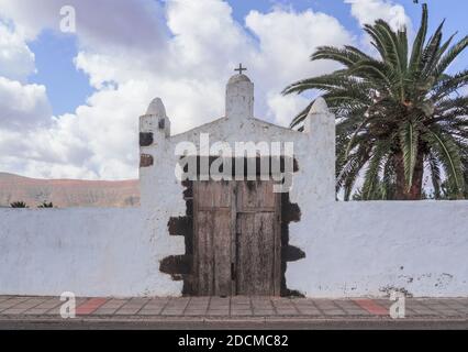 entrée d'un bâtiment rural blanc typique avec des palmiers de fond et porte en bois.Fuerteventura, îles Canaries, Espagne. Banque D'Images