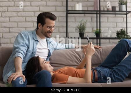 Un couple joyeux et détendu de la famille du millénaire regardant une vidéo amusante sur un smartphone. Banque D'Images