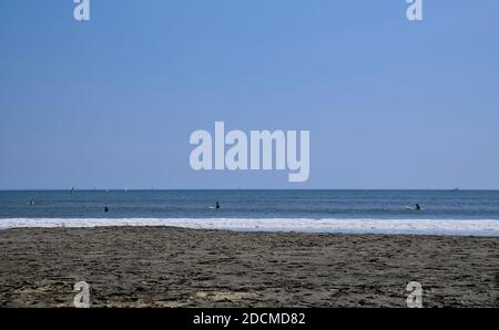 Vue de jour sur l'océan depuis la plage de Katase Higashihama par temps clair, avec plusieurs surfeurs et bateaux visibles au loin Banque D'Images