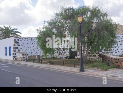 Bâtiment rural blanc typique avec des palmiers d'arrière-plan décorés de pierres de lave.Fuerteventura, îles Canaries, Espagne Banque D'Images