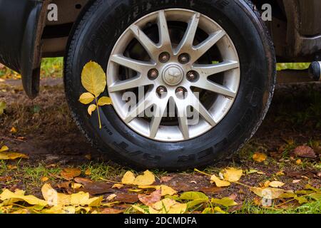 Anapa, Russie - 11.22.2020: Feuilles jaunes humides collées au pneu d'une voiture Mitsubishi le jour de l'automne. Changement de saison, réorganisez les pneus pour l'hiver Banque D'Images