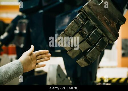 Gros plan d'une fille tire sa main vers le bras du robot. La technologie et le concept de l'avenir de l'humanité. Intelligence artificielle humaine bionique Banque D'Images