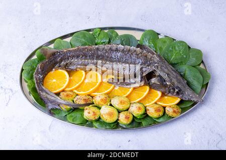 Sterlet cuit (esturgeon) avec des épinards, des oranges et des choux de Bruxelles. Cuisine russe. Gros plan. Banque D'Images