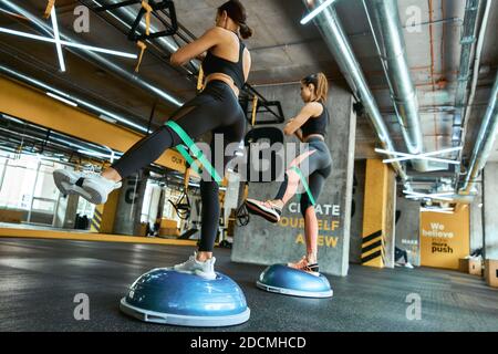 Travailler dur. Deux jeunes femmes sportives en sport s'entraînant avec un bracelet de résistance au crossfit Gym, utilisant des équipements sportifs spéciaux. Entraînement, entraînement, bien-être et mode de vie sain concept Banque D'Images