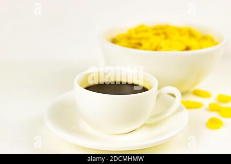 Flocons de maïs dans un bol blanc, tasse de café noir expresso sur fond blanc petit déjeuner Banque D'Images
