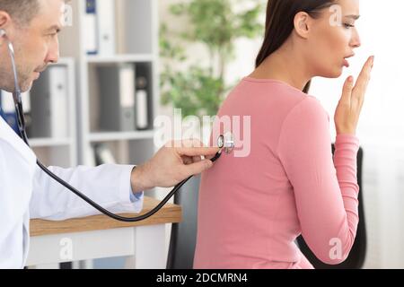 Médecin de sexe masculin vérifiant la respiration d'une patiente Banque D'Images