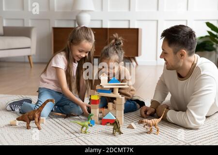 Le père joue avec la tour de bâtiment des filles avec des blocs de bois Banque D'Images