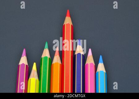 La direction fait des différences par des crayons de couleur sur fond noir, représentant le concept de se démarquer de la foule Banque D'Images