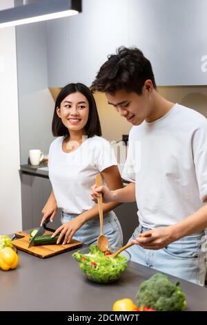 Couple asiatique debout dans la cuisine moderne cuisine ensemble, vertical Banque D'Images