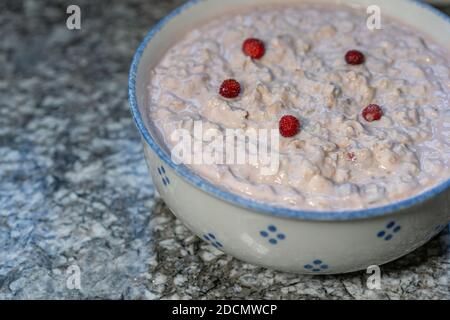 Yaourt frais avec céréales, fruits en tranches, banane, pomme, décoré de petites fraises des bois. Préparé des muesli bircher suisses. Copier l'espace. Banque D'Images