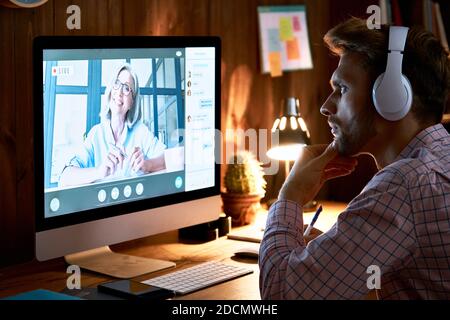 Un étudiant sérieux portant un casque, suivant un cours en ligne et regardant un séminaire en ligne. Banque D'Images