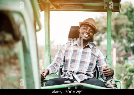 Travailleur africain conduisant des équipements de construction lourds de pelle rétro avec sourire et heureux Banque D'Images