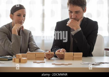 Les partenaires d'affaires hommes et femmes construisent un pont de blocs de bois ensemble dans une image conceptuelle de partenariat. Banque D'Images