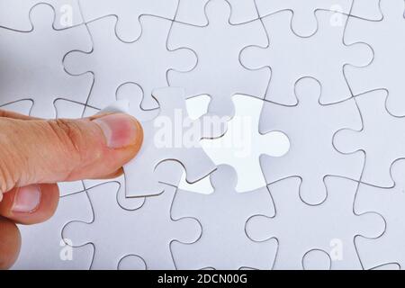 Fond blanc de motif de puzzle. Placement de la dernière pièce de puzzle Banque D'Images