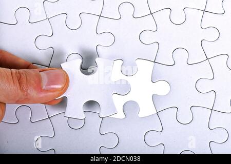 Fond blanc de motif de puzzle. Placement de la dernière pièce de puzzle Banque D'Images