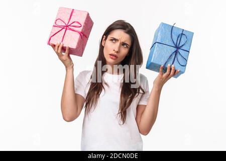 Célébration, fêtes et cadeaux concept. Hmmm intéressant ce qui à l'intérieur. Portrait de curieux jeune fille d'anniversaire secouant des boîtes-cadeaux essayant de Banque D'Images