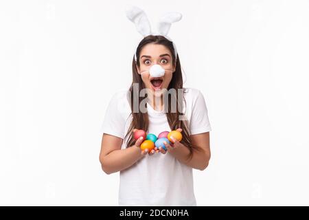 Portrait de jeune femme drôle et heureuse, portant un costume de lapin, des oreilles et un masque de nez molletonné, tenant des œufs de couleur, célébrant la fête de Pâques des vacances Banque D'Images