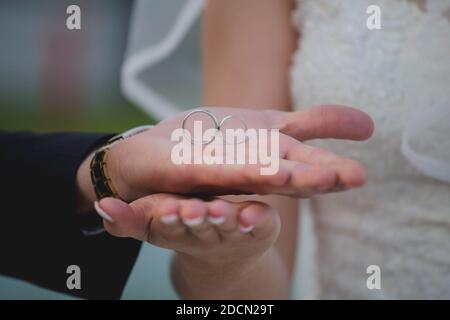 Un gros plan du marié tenant les anneaux de mariage la paume de sa main au-dessus de la main de la mariée Banque D'Images