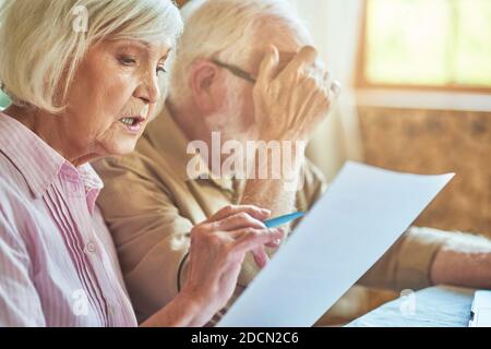 Gros plan d'un couple marié âgé assis à table dans leur maison tout en gérant leur budget. Concept de famille et de ménage Banque D'Images