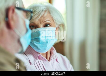 Photo rognée d'une femme âgée regardant son mari tout en portant des masques de protection à la maison. Concept de soins et de santé Banque D'Images